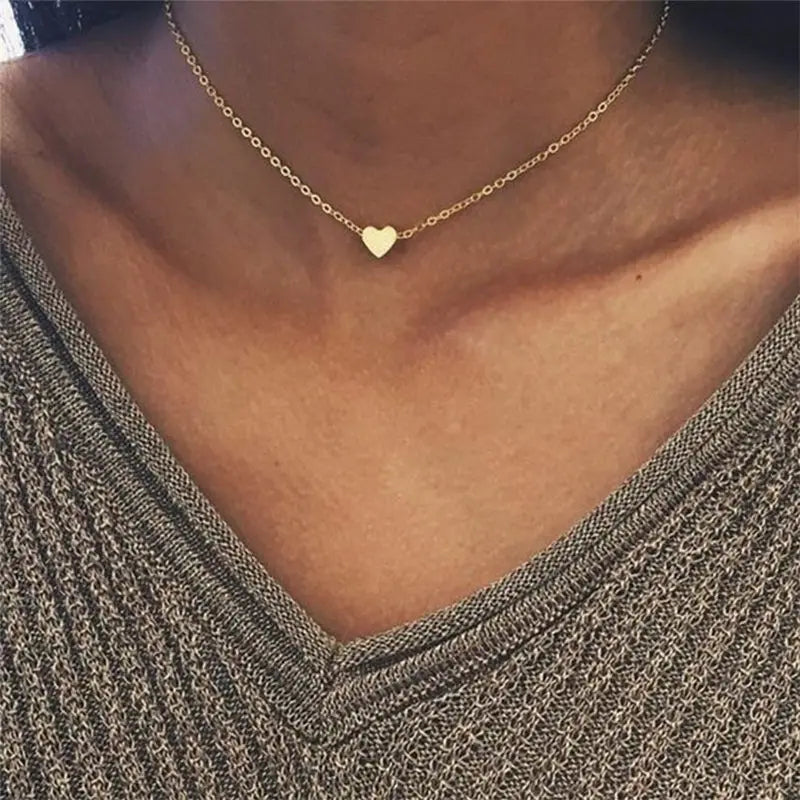 Gold-color chain choker necklace featuring a small heart pendant centered on the collarbone.