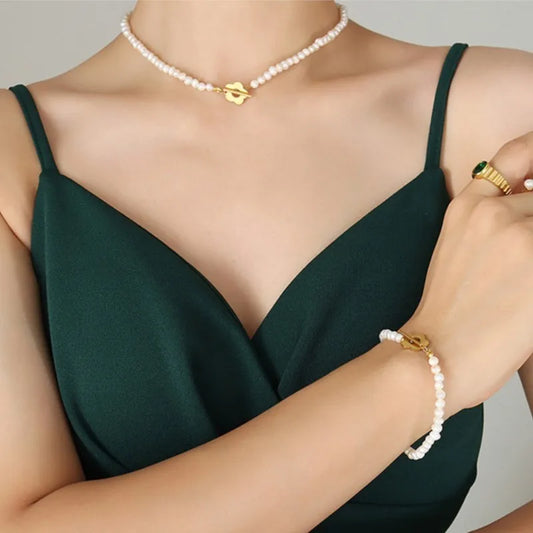 Small white pearl necklace and matching bracelet featuring gold flower toggle clasps worn by a woman.