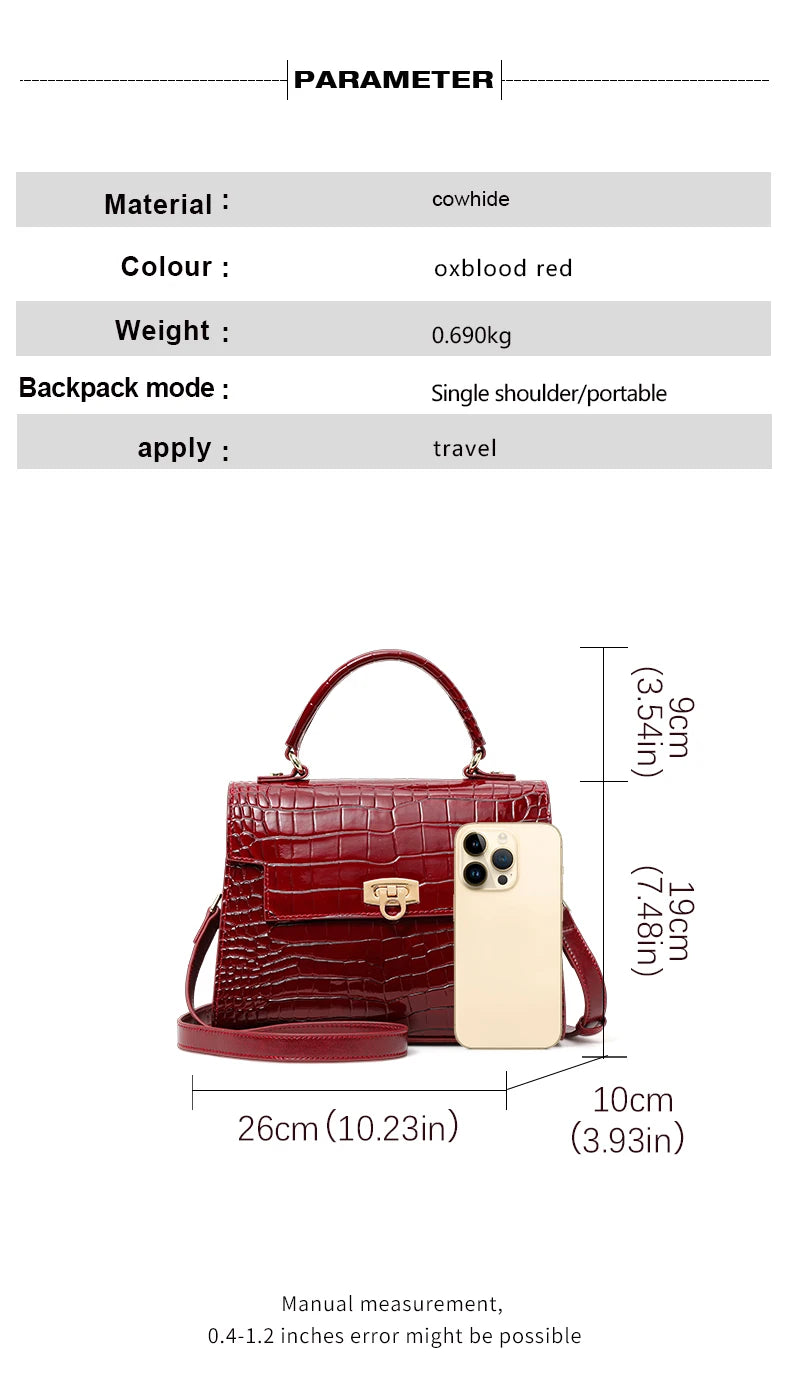 Oxblood red cowhide handbag with crocodile pattern, top handle, flap closure, and a gold clasp, shown with a phone for scale.