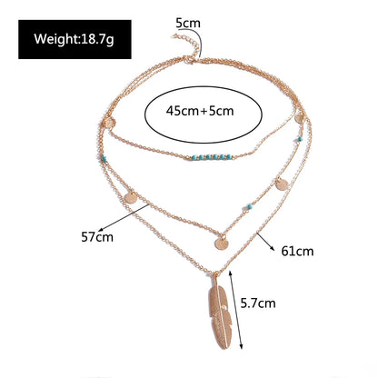 Gold-colored multilayer metal chain necklace with turquoise beads, coin charms, and a feather pendant.