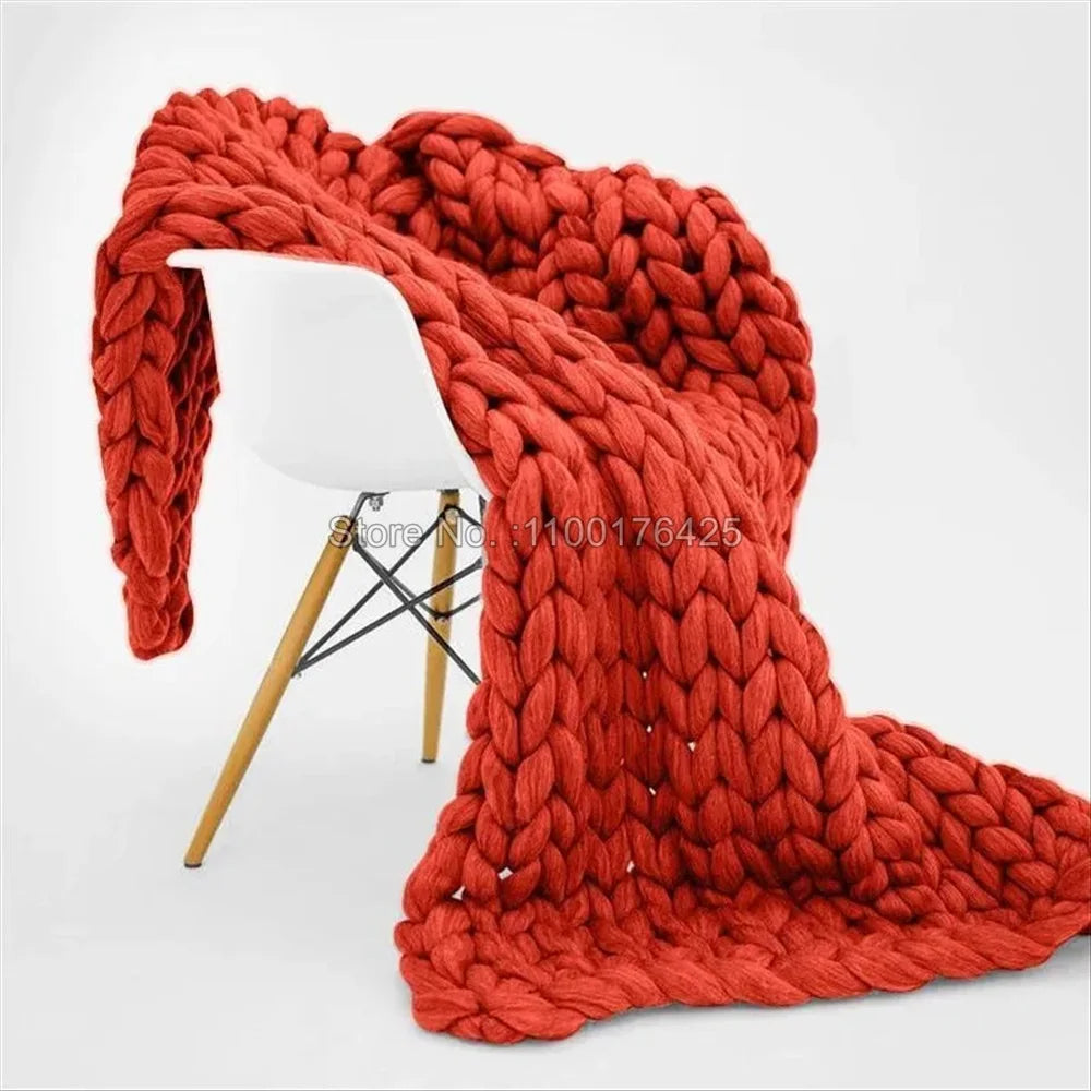 Chunky orange-red hand-knitted yarn roving throw blanket draped over a modern white chair.