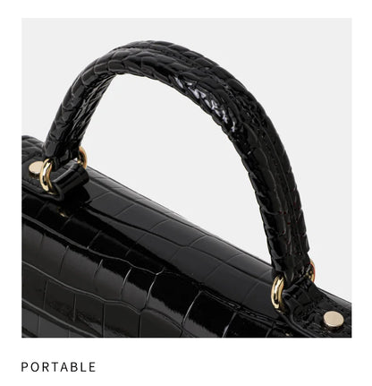 Black patent leather handbag with crocodile pattern, top handle, and gold-tone hardware.