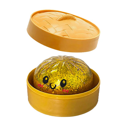 Gold glittery dumpling squishy fidget toy inside a round yellow plastic steaming basket for sensory play.