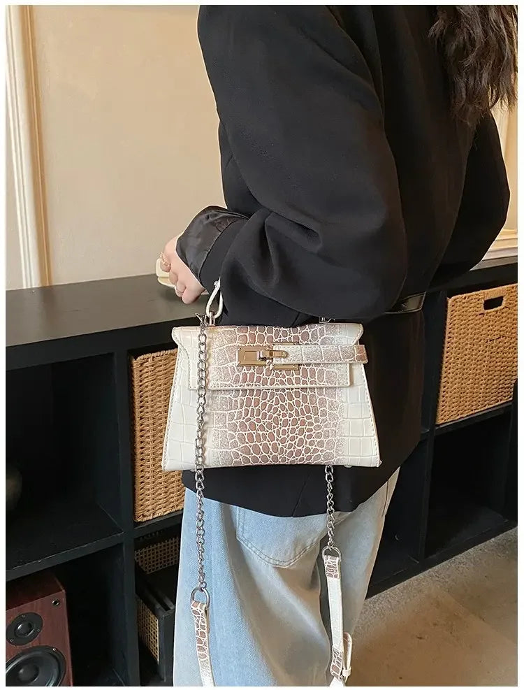 Off-white crocodile-embossed faux leather crossbody bag with chain strap for organizing baby essentials.