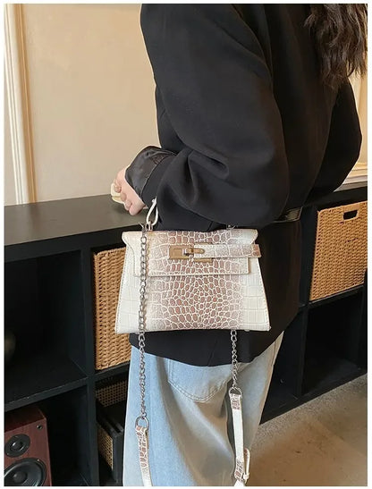 Off-white crocodile-embossed faux leather crossbody bag with chain strap for organizing baby essentials.