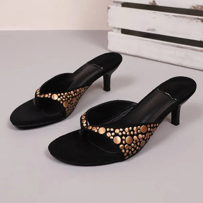 Black suede stiletto sandals featuring gold rivet details, ideal for evening wear.
