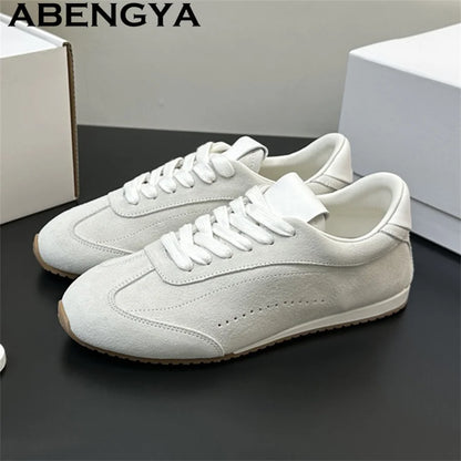Off-white suede lace-up casual sneakers with white laces, white lining, and thin brown rubber soles.
