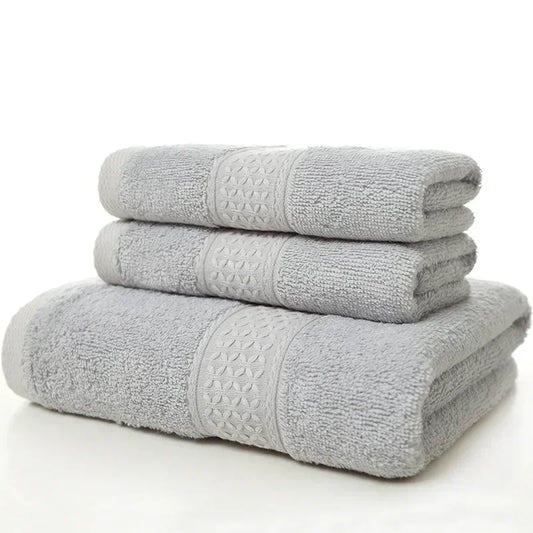 A stack of three folded light gray bath towels with decorative patterned bands.