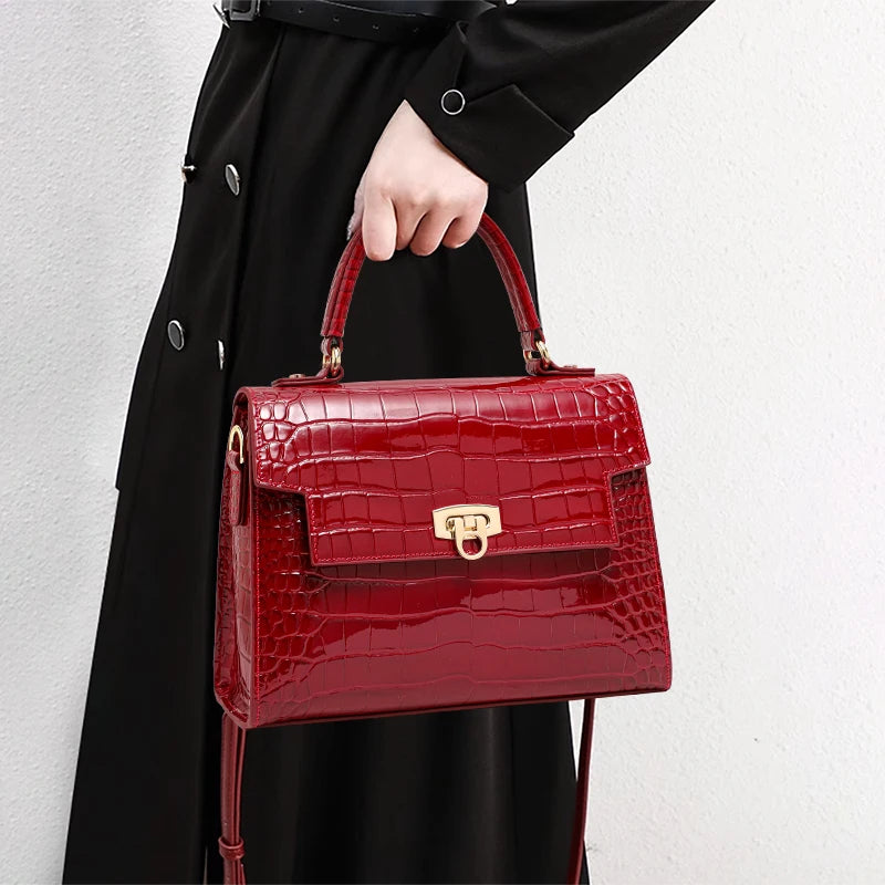 Glossy red crocodile-embossed leather handbag with a top handle, flap closure, and gold-tone hardware.