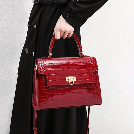 Glossy red crocodile-embossed leather handbag with a top handle, flap closure, and gold-tone hardware.