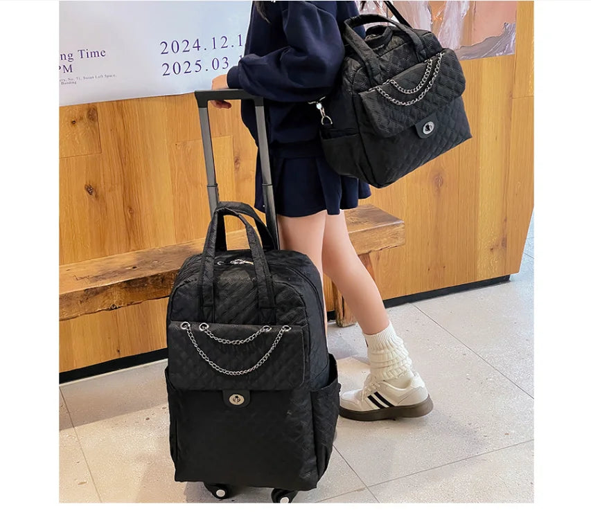 Black quilted rolling travel backpack with a front pocket featuring a silver chain detail and a retractable handle.