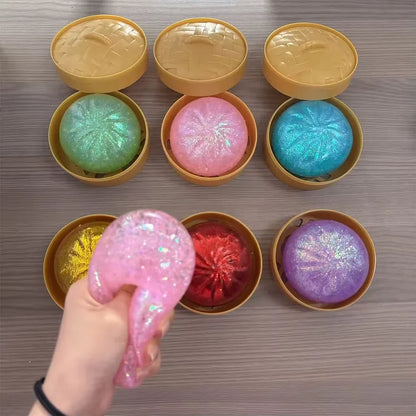 Glittery, stretchy dumpling squishy fidget toy in mini plastic steamer baskets for sensory play and stress relief.