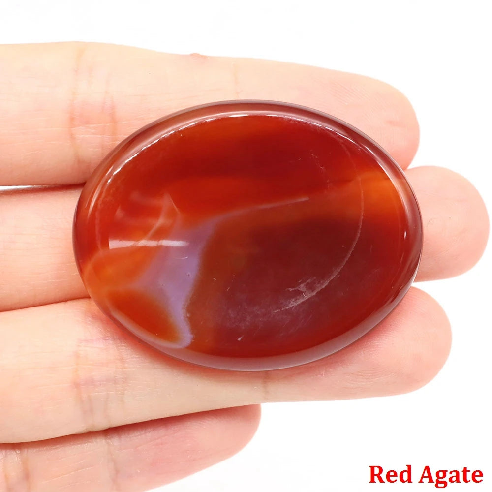 Smooth, oval red agate home decor palm stone held in hand for meditation.