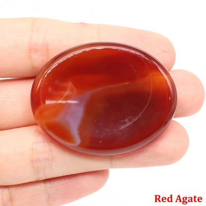 Smooth, oval red agate home decor palm stone held in hand for meditation.