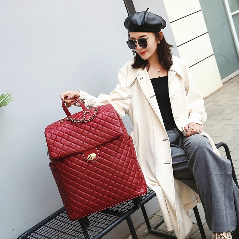 Red quilted PU rolling suitcase with a flap closure, gold-tone hardware, and a chain detail.