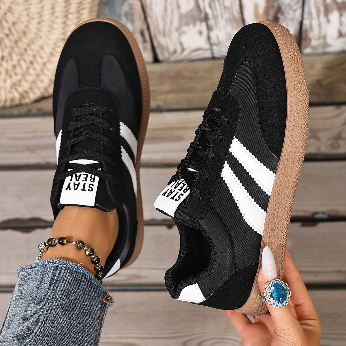 Black leather slip-on sneakers with white stripes, gum soles, and logo tongue for casual daily wear.