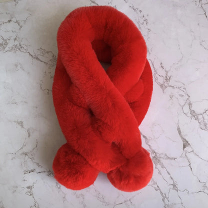 A solid red plush faux fur cross scarf with two pom-pom ends.