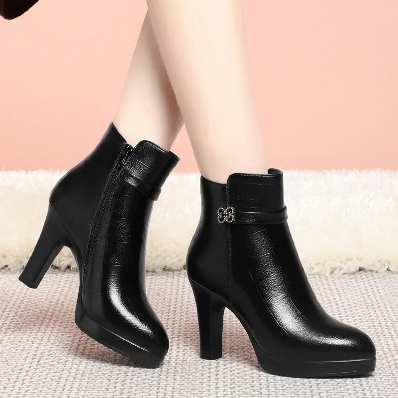 Black leather ankle boots with high block heels, platform soles, side zippers, and decorative ankle straps with buckles.