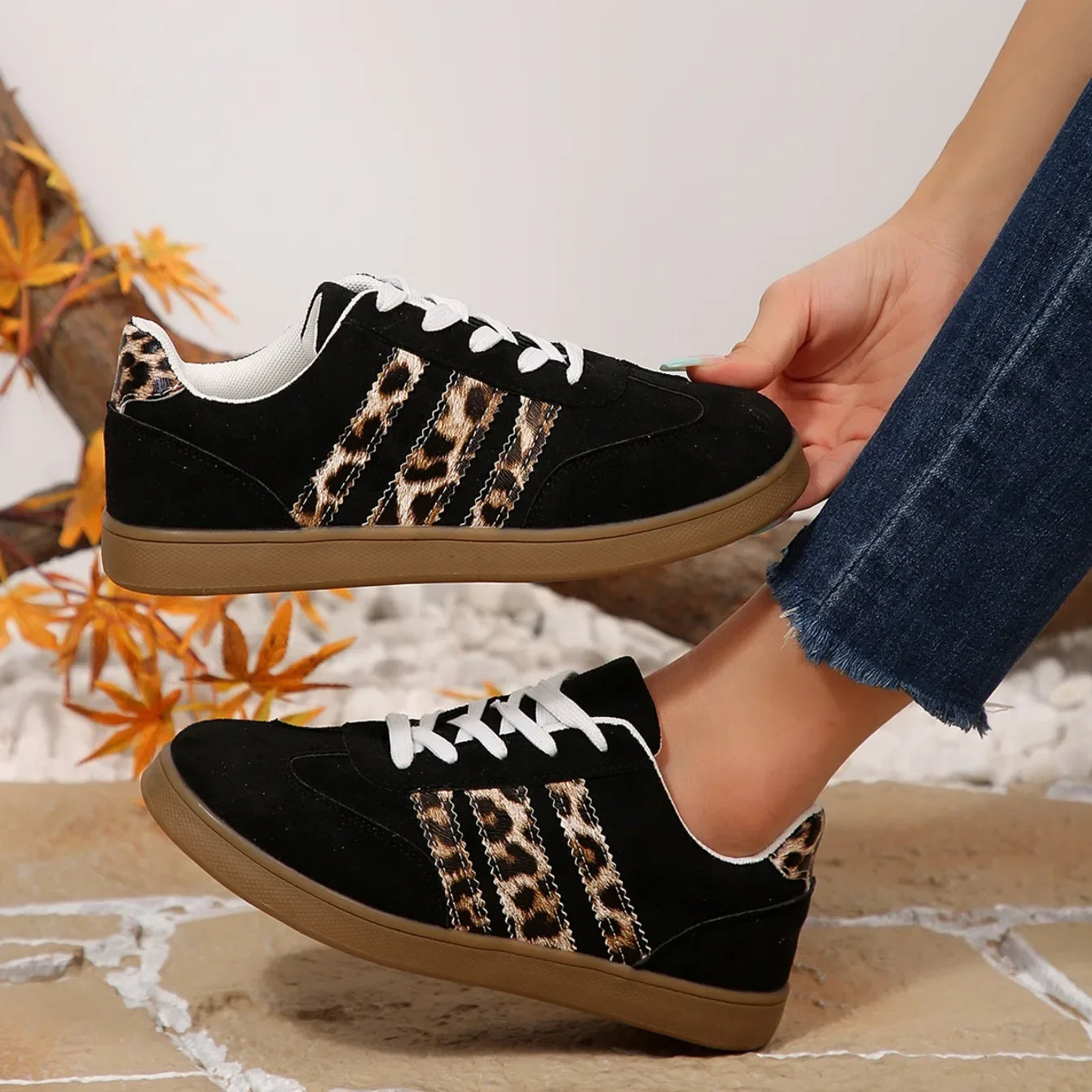 Black suede sneakers with leopard print stripes, white laces, and cushioned soles for outdoor walking.
