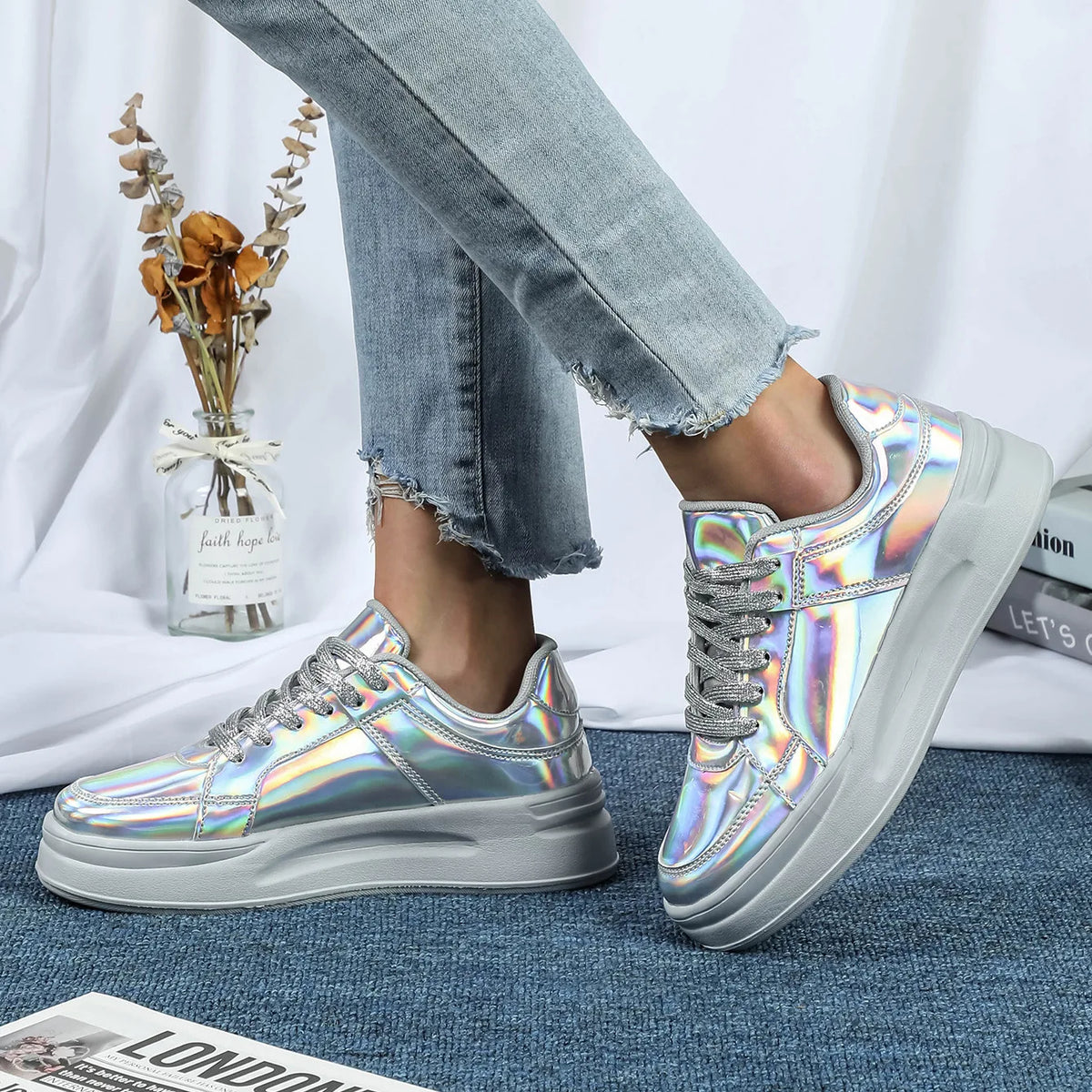 Silver metallic sequin casual sneakers with thick grey soles, lace-up style, and metallic laces worn with jeans.