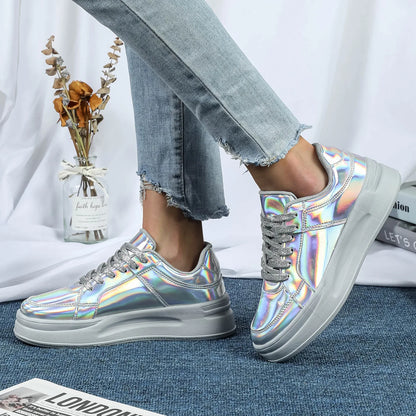 Silver metallic sequin casual sneakers with thick grey soles, lace-up style, and metallic laces worn with jeans.