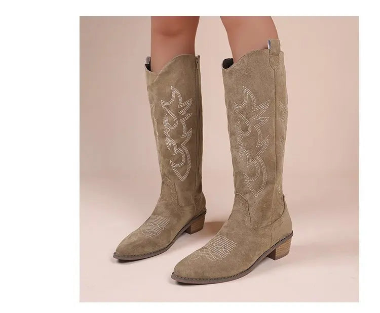 Tan suede knee-high Western cowboy boots with white embroidery and block heels.