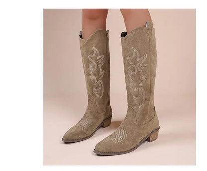 Tan suede knee-high Western cowboy boots with white embroidery and block heels.