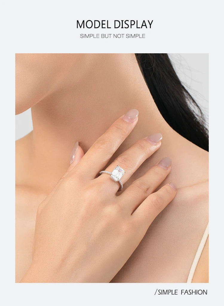 A silver sterling ring with a large rectangular center stone and pavé band worn on a woman's finger.