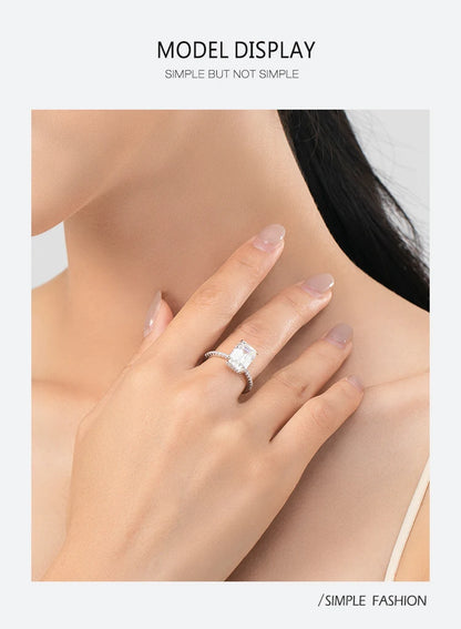 A silver sterling ring with a large rectangular center stone and pavé band worn on a woman's finger.