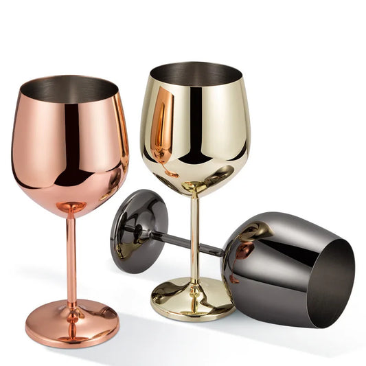 Three stainless steel wine goblets in rose gold, gold, and gunmetal finishes, with one standing upright and two resting.