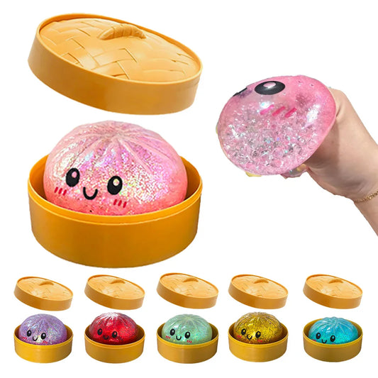 Pink glittery dumpling squishy fidget toy in a yellow plastic steamer for stress relief and sensory play.