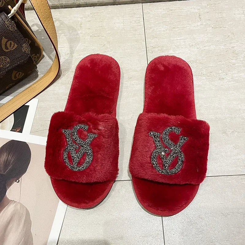 Red faux fur slippers with a crystal logo, non-slip sole, and soft lining for lounging at home.