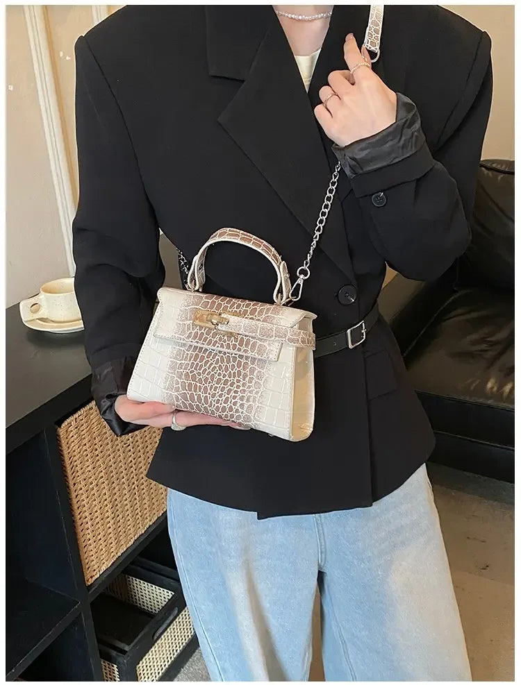 Beige faux leather structured satchel with croc texture and chain strap for organized baby gear carrying.
