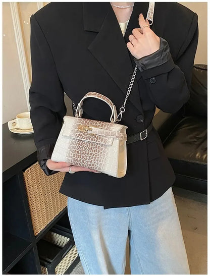 Beige faux leather structured satchel with croc texture and chain strap for organized baby gear carrying.