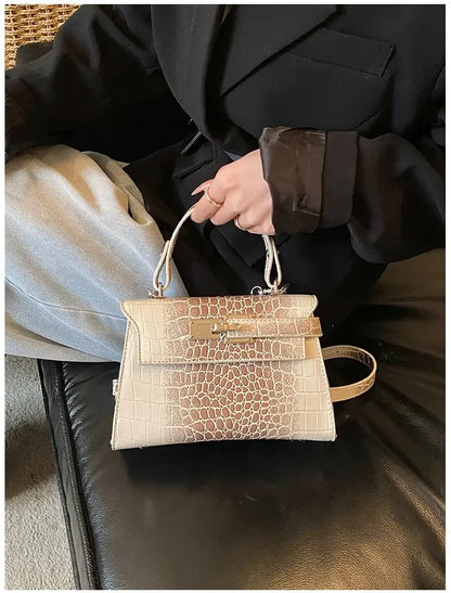 Beige faux leather structured diaper bag with crocodile texture and metal clasp for organized parenting on the go.