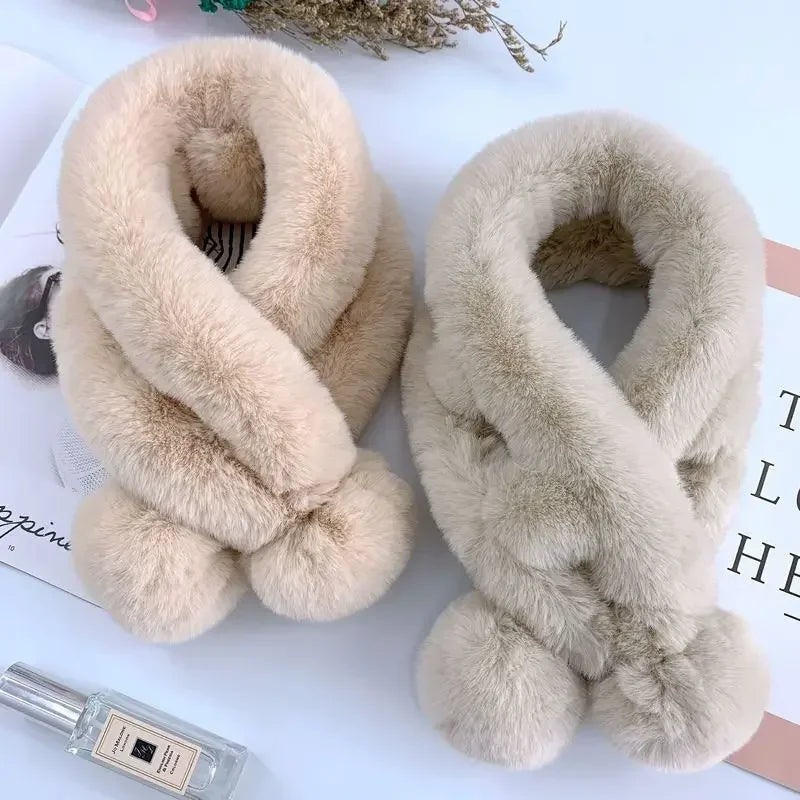 Two soft, plush faux fur cross scarves in beige and light gray, featuring dual pom-pom ends.