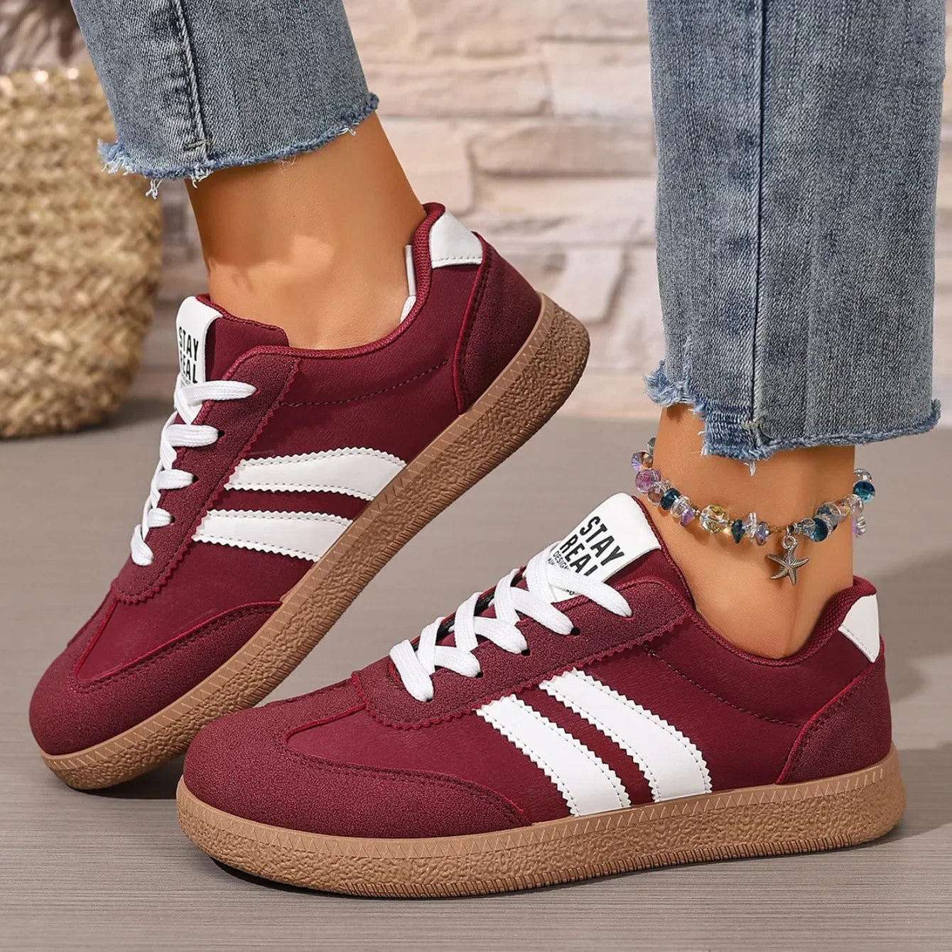 Maroon leather slip-on sneakers with white stripes, white laces, and gum soles for casual daily wear.