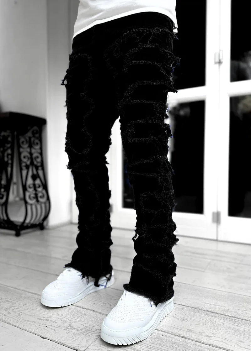 Black distressed denim jeans with frayed patchwork details and a fitted silhouette for casual everyday wear.