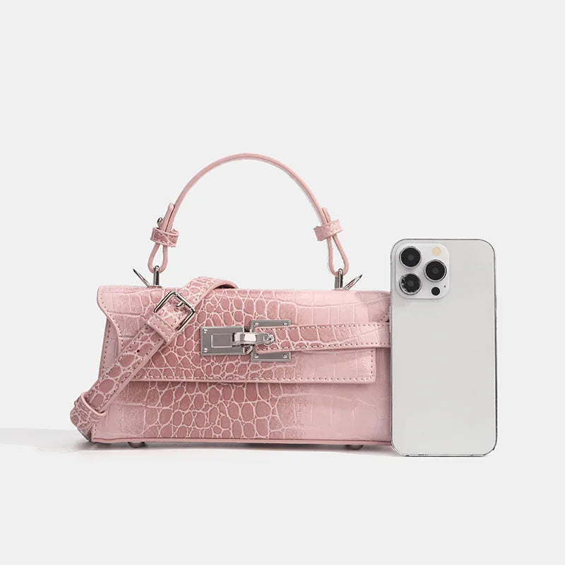 Pink faux leather crossbody with croc texture, silver clasp, and adjustable strap for everyday essentials.