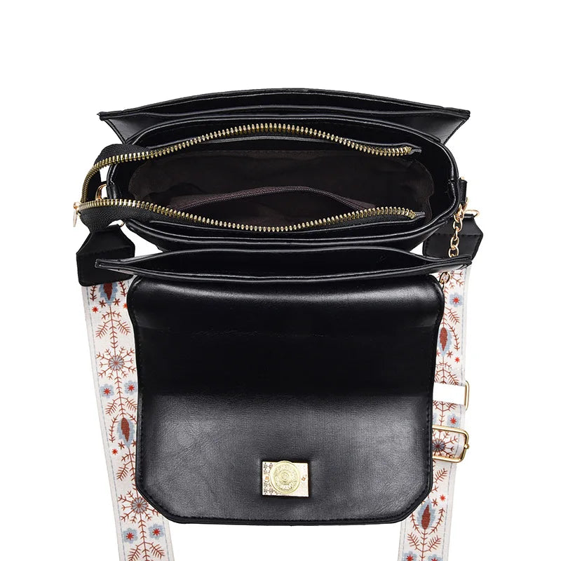 Black faux leather shoulder bag, top-down view showing zippered compartments and a patterned strap.