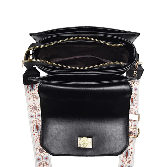 Black faux leather shoulder bag, top-down view showing zippered compartments and a patterned strap.