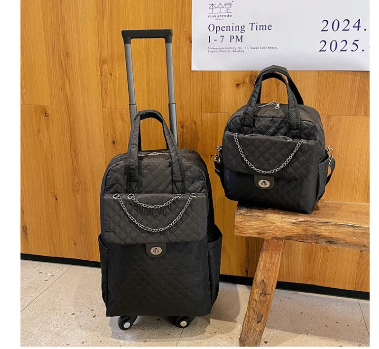 Black quilted nylon rolling travel backpack and matching tote bag with chain strap and turn-lock pocket.
