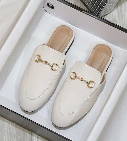 Cream, closed-toe slip-on shoes with gold metal chain detail for casual outdoor wear.