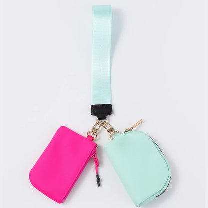 Pink and mint nylon zip closure wristlet wallet with a detachable strap for carrying keys and cards.