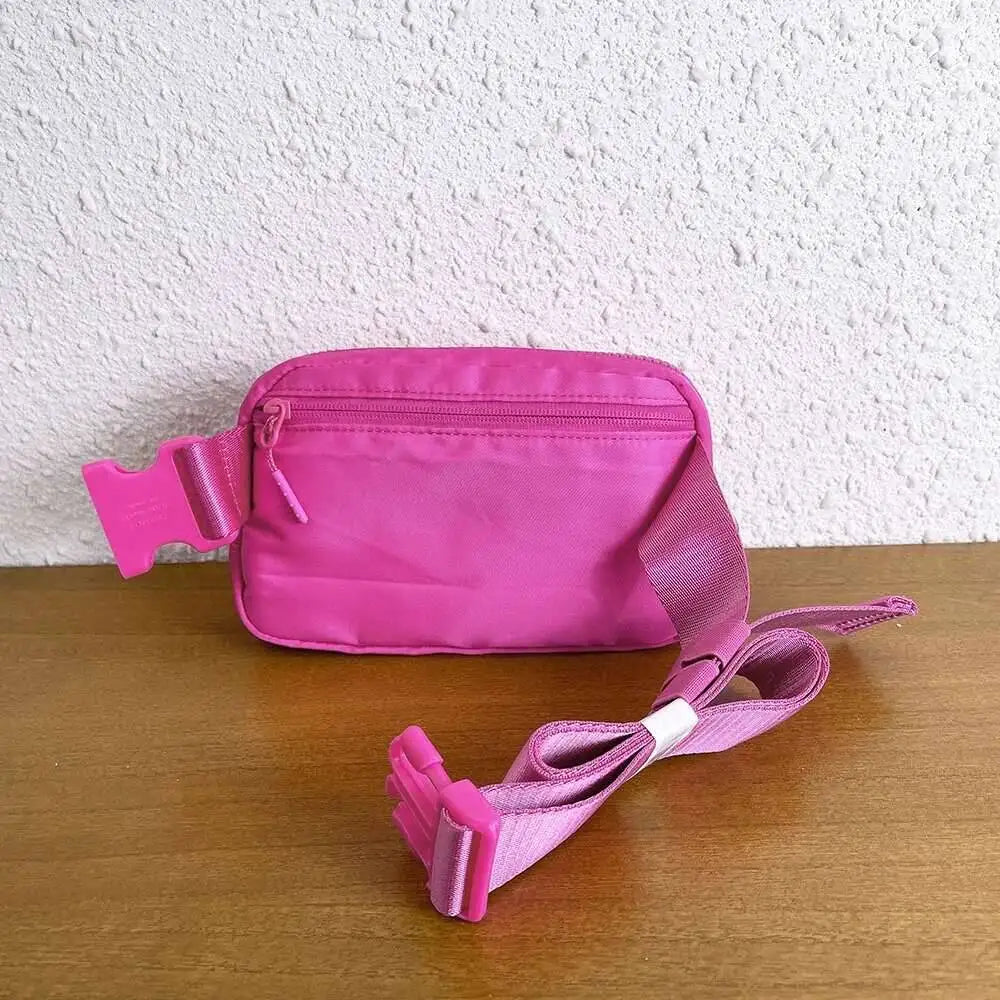 Hot pink nylon crossbody bag with zip closure and adjustable strap for running.