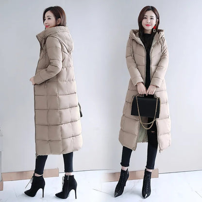 Woman wearing a beige, quilted long down winter coat with a hooded parka style and zippered front.