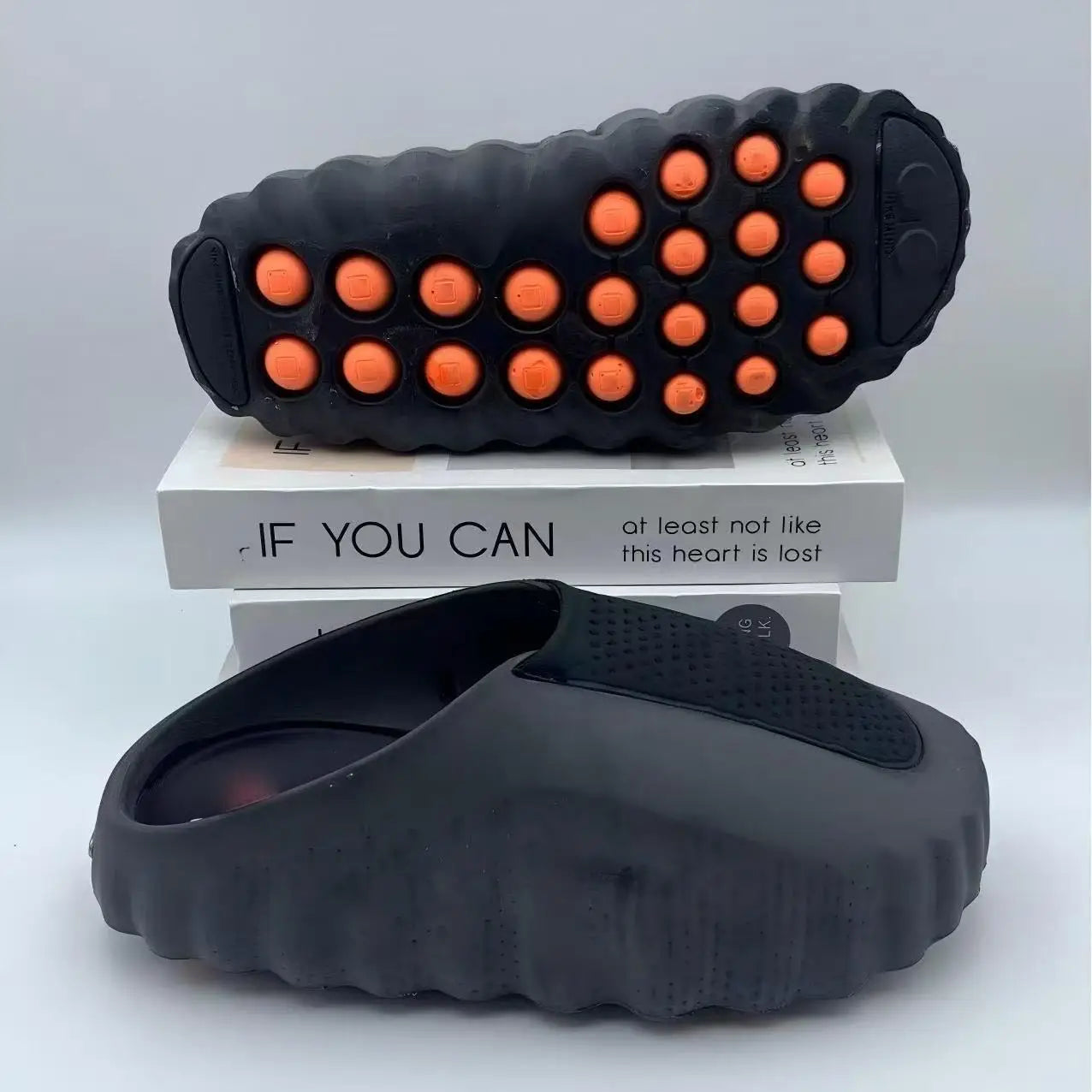 Black EVA sandals with orange massage nodules on a cushioned, non-slip sole for daily wear.