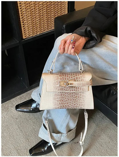 Beige faux leather crossbody diaper bag with croc-embossed texture and zip closure for carrying baby essentials.