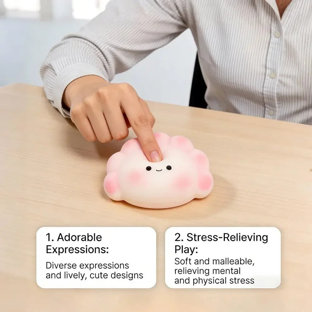A white, soft dumpling squishy fidget toy with pink cheeks, used for stress relief on a desk.