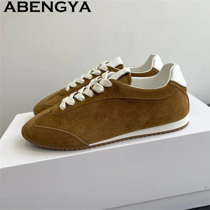 Brown suede casual sneakers with white laces, white heel tabs, and thin white soles.